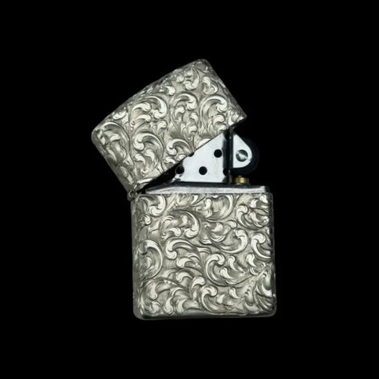 Zippo lighter in silver that has been hand engraved with a wave scroll pattern.