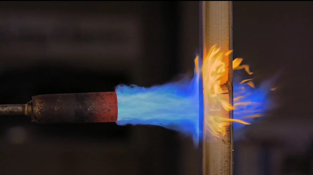 Bamboo culm being heat-treated and colored with a torch flame during fly rod making process.